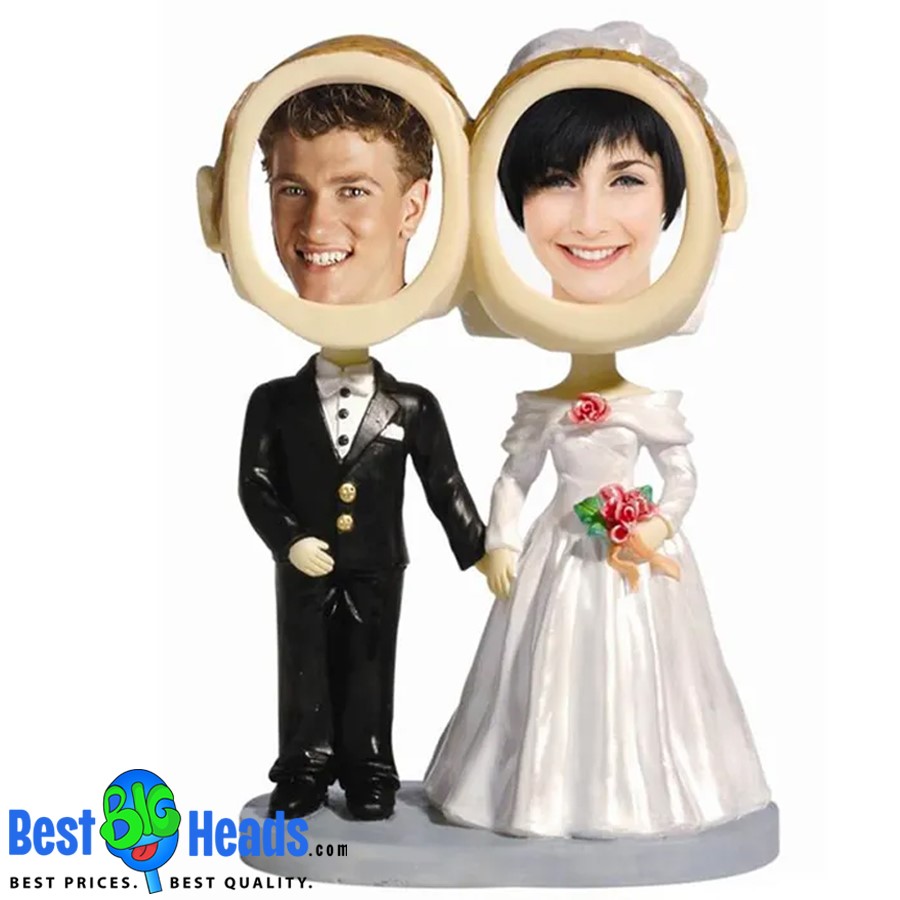 A custom wedding bobblehead featuring a bride and groom with oversized heads. The figurines are dressed in formal wedding attire, with the groom in a black tuxedo and the bride in a white gown, holding a bouquet.